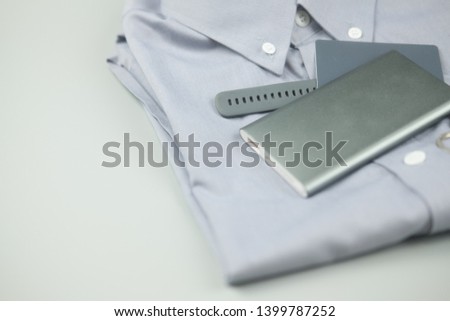 Gray colour clothing and electronic item gray colour (silver power bank, smart watch and credit card) on gray background