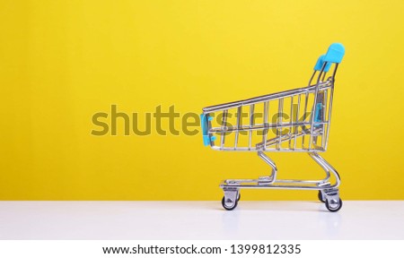 Shopping trolley on desk with yellow background. Concept image.                              
