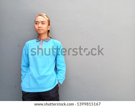 Young man standing on gray background. Man with blue shirt  looking. Photo for making advertise, banner and other.