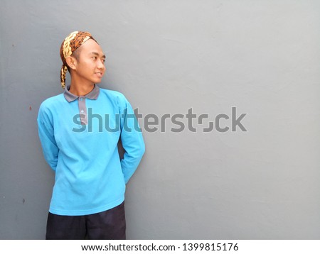 Young man standing on gray background. Man with blue shirt  looking. Photo for making advertise, banner and other.