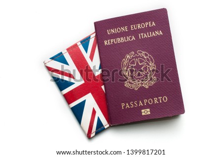 An italian passport on top of the union jack flag on white background