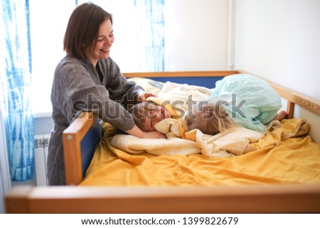 children hugs play with their mother on a children's bed, happy siblings embrace next to their mom. The concept of childhood and motherhood, lifestyle in the real interior