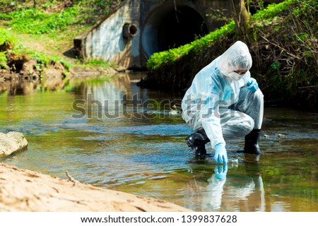 ecological disaster, contaminated water comes out of the sewage system - an ecologist takes a sample of water for research Royalty-Free Stock Photo #1399837628