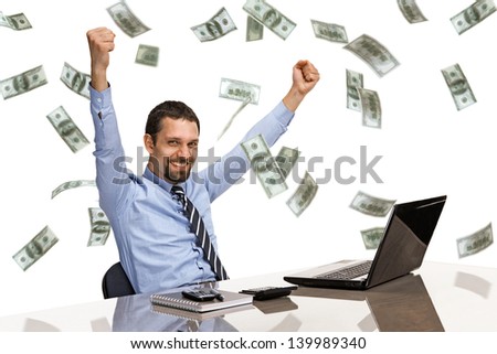 businessman with his hands raised while working on laptop with money rain 