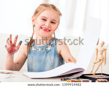 Cute female child is using her hands as palette, close-up