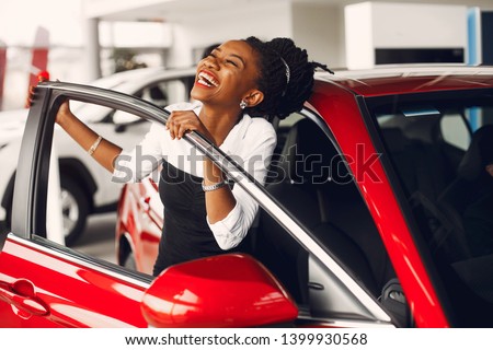 Woman buying the car. Lady in a car salon. Elegant black girl Royalty-Free Stock Photo #1399930568