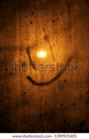 symbol of a smile on a frozen window on a sunset background