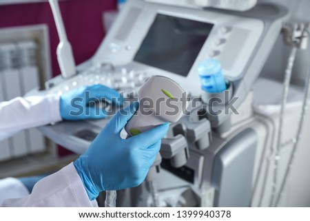 Sonographer holding ultrasound machine probe in clinic, closeup Royalty-Free Stock Photo #1399940378