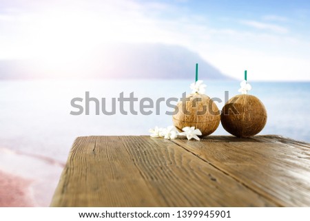 Table background of free space for your decoration. Fresh coconuts with flowers and beach landscape 