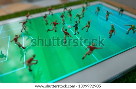 Side view of miniature toys figurines football (soccer) players on a computer pad.