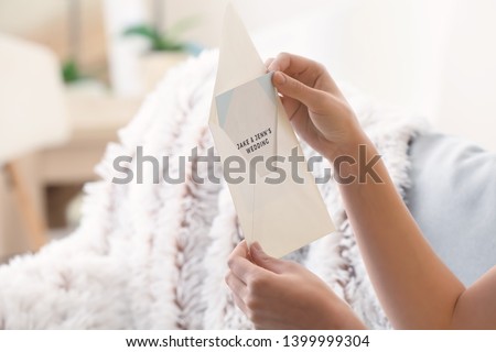 Young woman with wedding invitation at home