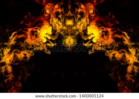 Abstract image of smoke of different green, yellow, orange and red colors in the form of horror in the shape of the head, face and eye on a black isolated background. Soul and ghost in mystical symbol