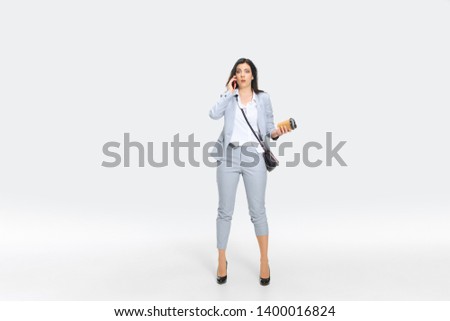 Another minute and you're fired. Young woman in gray suit is getting shocking news from boss or colleagues. Looking numbed while dropping coffee. Concept of office worker's troubles, business, stress.