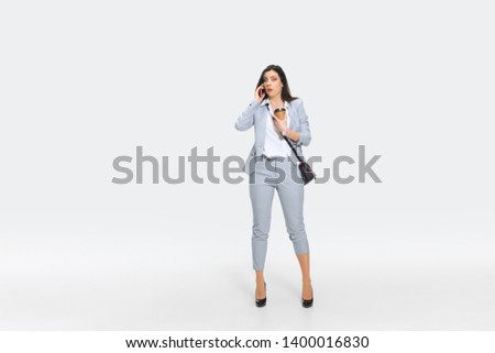You are fired from yesterday. Young woman in gray suit is getting shocking news from boss or colleagues. Looking numbed while dropping coffee. Concept of office worker's troubles, business, stress.