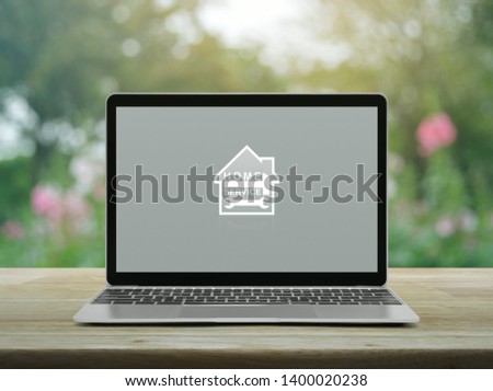 Hammer and wrench with house flat icon with modern laptop computer on wooden table over blur pink flower and tree in garden, Business home service online concept