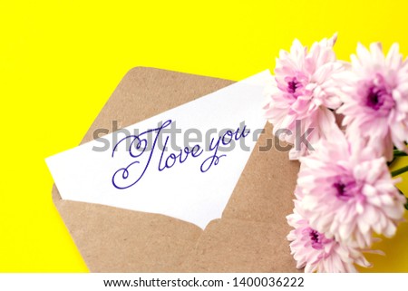 Love envelope and letter with written words I love you with pink chrysanthemum flowers on bright yellow bacground. 
