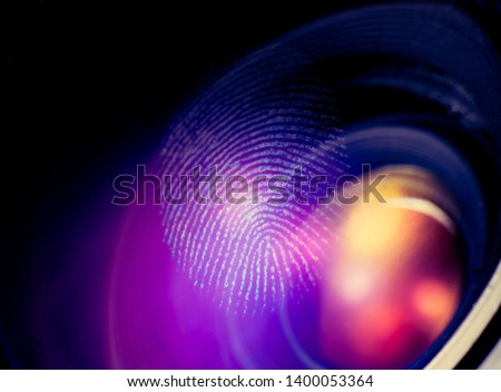 Fingerprint macro on a lens, dark background. Thumbprint on glass. Biometrics, crime, surveillance and security concept.