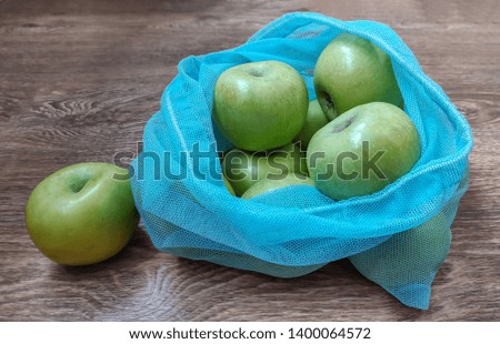 Picture of green apples in reusable eco bags for fruits and vegetables on wooden surface. Zero waste and recycling movement. Use by greengrocery, zero waste shops, cooking books