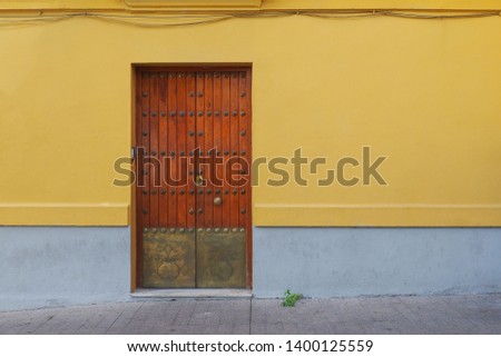 The exterior facade with a antique wooden door and yellow wall