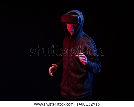 Model young man in glasses of virtual reality on dark background. Augmented reality, future technology concept. VR. Neon red light.
