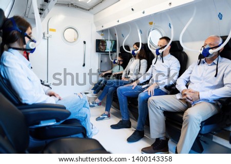 Group of mixed age people wearing masks while having oxygen therapy in hyperbaric chamber.  Royalty-Free Stock Photo #1400143358