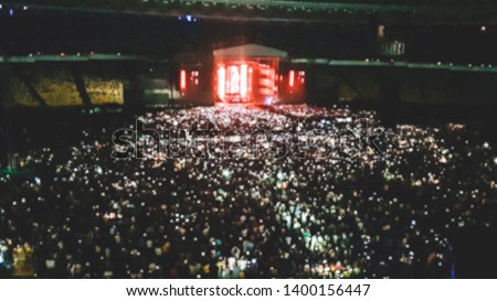 Defocused image of big stadium full of fans on the rock music concert. Perfect backdrop for illustrating party, disco or music festival