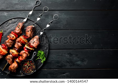 Shish kebab BBQ meat with onions and tomatoes. On a black background. Top view. Free space for your text. Rustic style. Royalty-Free Stock Photo #1400164547