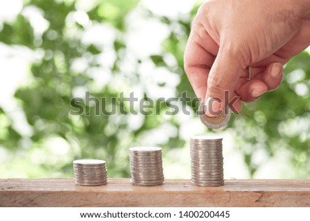 Cropped Hand Stacking Coins on Table with green bokeh background, Business success or Money growing concept