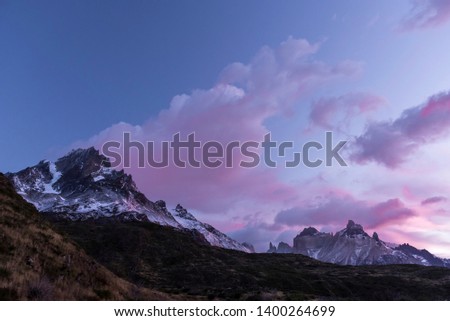 Picture shows a beautiful dawn of the mountains with purple clouds in Torres del Paine trekking.
