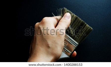           brush for painting in the hands of the walls on a black background                     