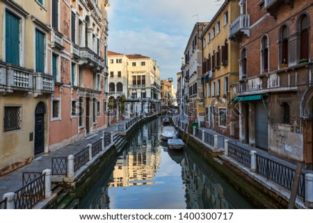 Photo of a romantic Venetian canal, old houses and empty sidewalks in the morning. Historic architecture of Italy. Popular travel destination in Europe