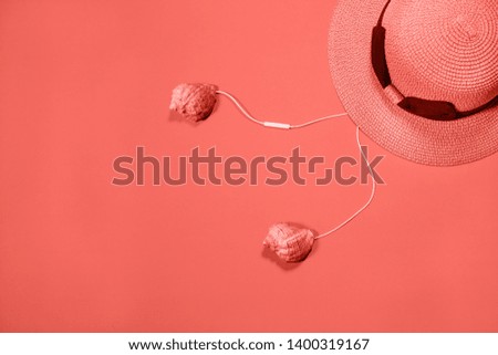 Living Coral 2019. Conceptual earphones and straw hat on coral colored background