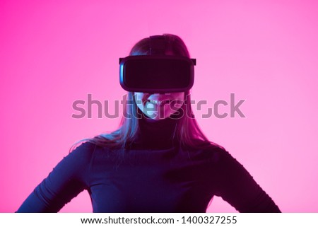 beautiful young girl wearing virtual reality glasses on a colored background
