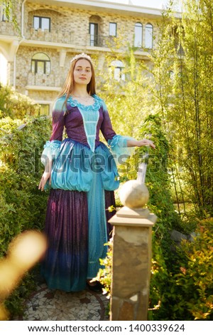 girl animator dressed as a medieval princess on the background of the castle in a beautiful park