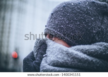 Girl very warmly dressed during a cold winter day covers her face with a thick scarf because really low temperatures outside. Photo take in Chicago during extremely cold and freezing winter day.
