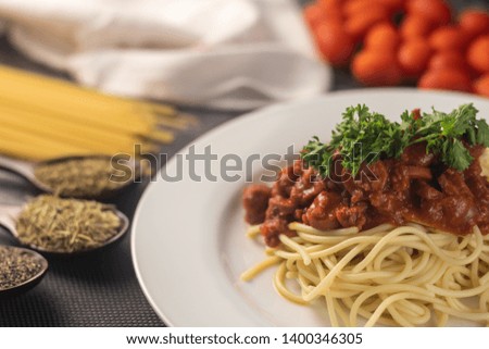 a plate of spaghetti served with the beef tomato sauce with ingredients on the mat. selective focus