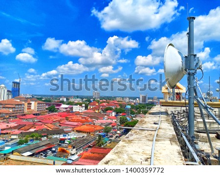 telecommunication tower antenna dish on building rooftop with a background of a city. telecom microwave antenna for 3g and 4g services on daylight stock photo -image