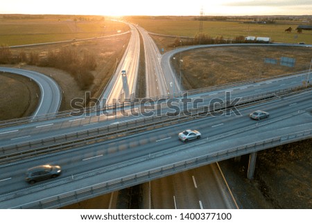 Aerial view of modern highway road intersection at dawn on rural landscape and raising sun background. Drone photography.