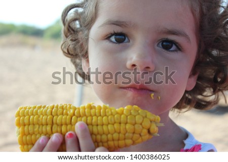 Little girl eating tasty corn