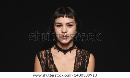 Woman with piercing on lips isolated on black background. Portrait of a young gothic woman looking at camera.