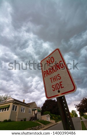 No Parking This Side sign with dark storm clouds in the background.