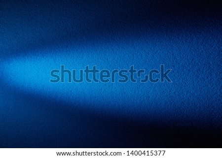 On a blue textural background a cone-shaped beam of light