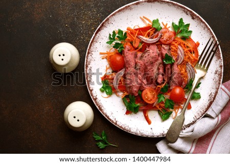 Vegetable salad with roast beef on a white plate on a dark slate, stone or concrete background. Top view with copy space.