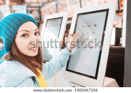 A woman orders food in the touch screen terminal with electronic menu in fast food restaurant Royalty-Free Stock Photo #1400467106