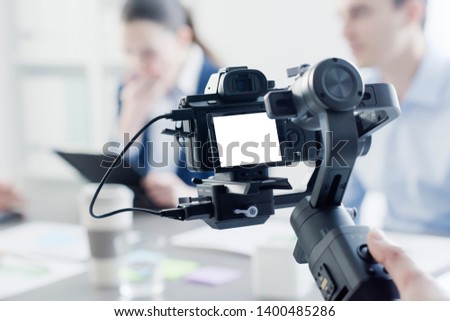 Professional videomaker shooting a video, defocused actors in the background, videomaking and communication concept