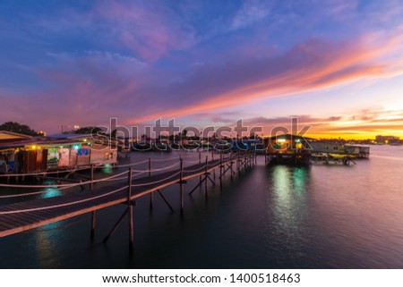 Beautiful twilight sunset with wooden jetty and water village house - Travel Concept.