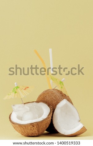 Fresh Coconut cocktail with a straws on yellow background, copy space.