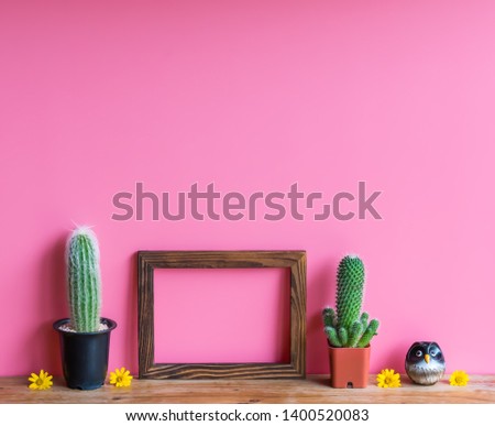 Beautiful  cactus,wooden  picture  frame  and  simulated  owl  on  pink  background