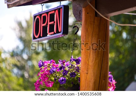 Neon open sign with colorful flower basket and log post in Talkeetna, Alaska