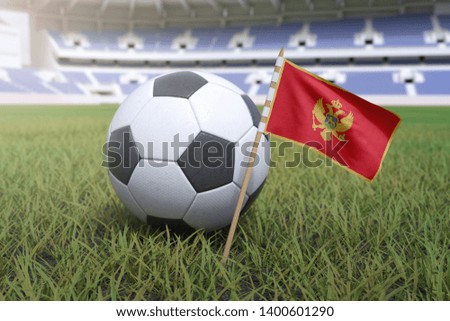 Montenegro flag in stadium field with soccer football